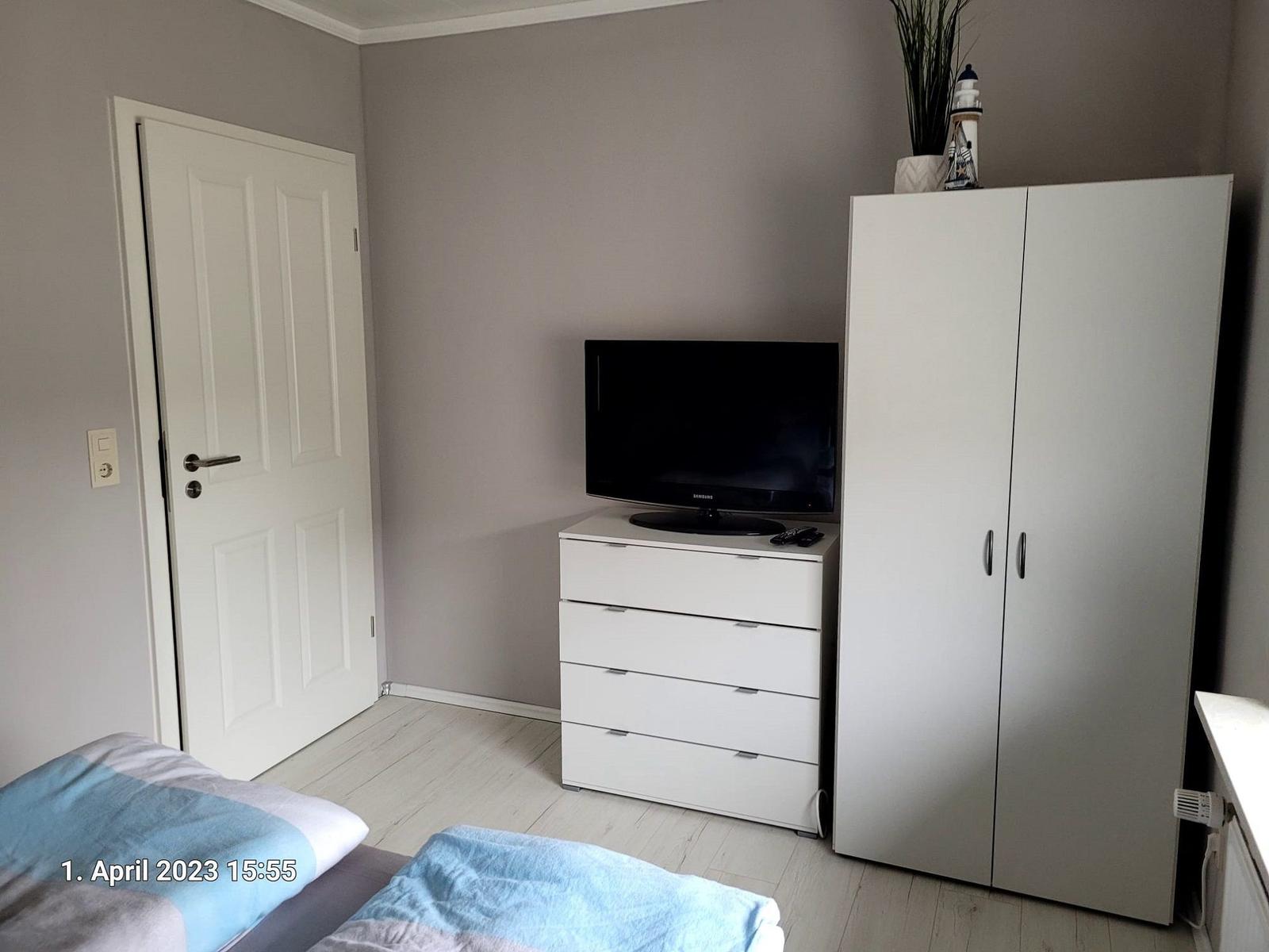 Schlafzimmer mit Bett, Kleiderschrank und Fernseher auf Schrank.