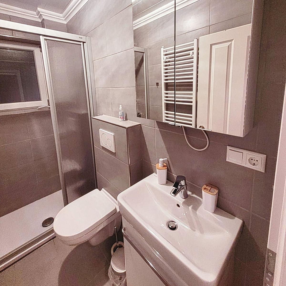 Badezimmer mit Dusche, WC und Waschbecken.