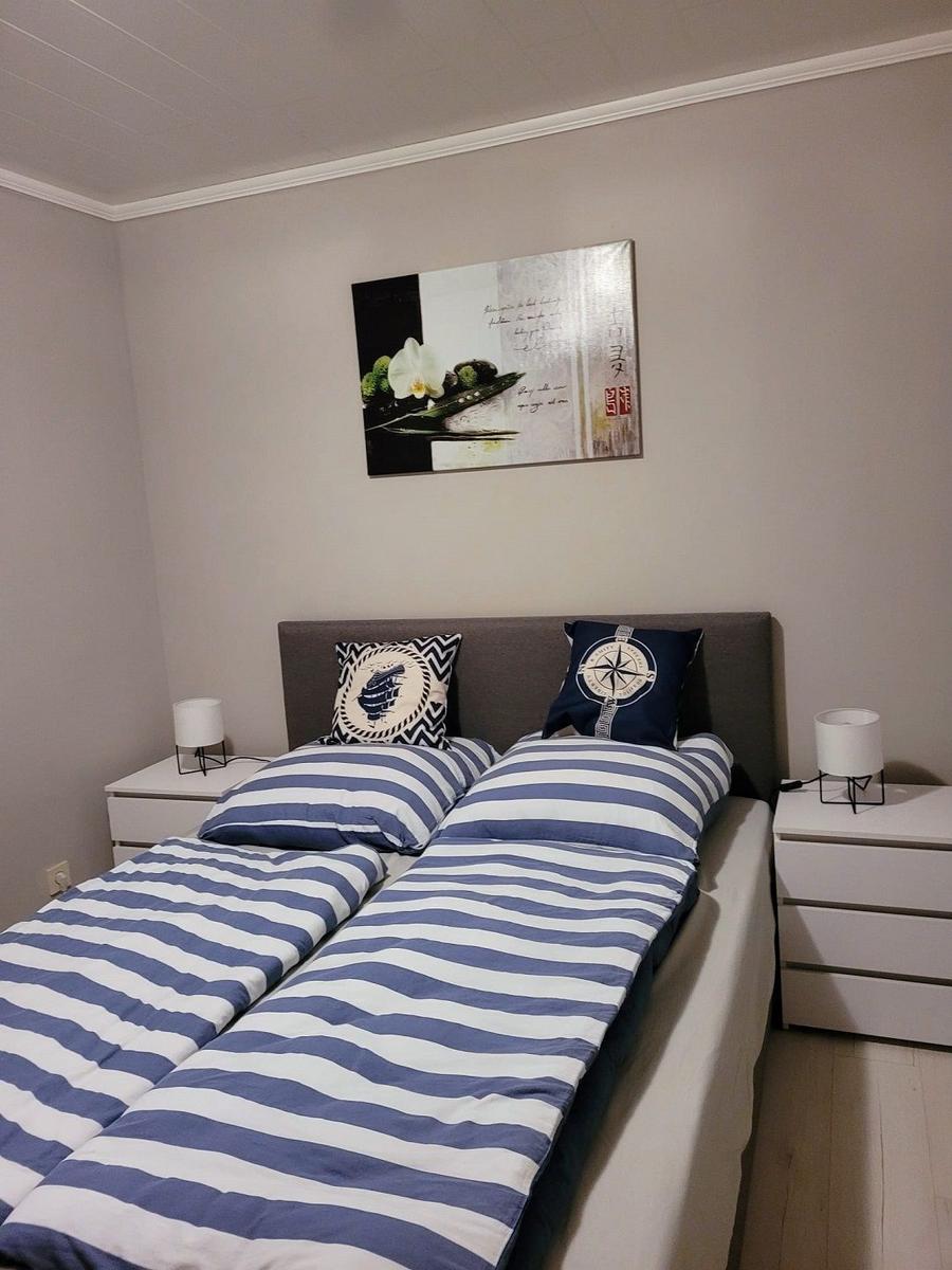 Schlafzimmer mit Doppelbett, zwei Nachttischen und Wandbild.