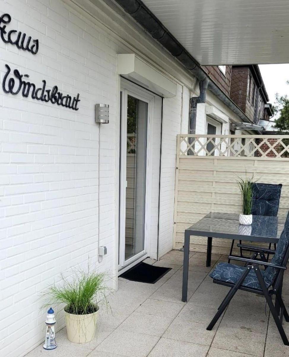 Haus Windsbraut mit Terrasse, Tisch, Stühlen und Pflanzen an der weißen Wand.