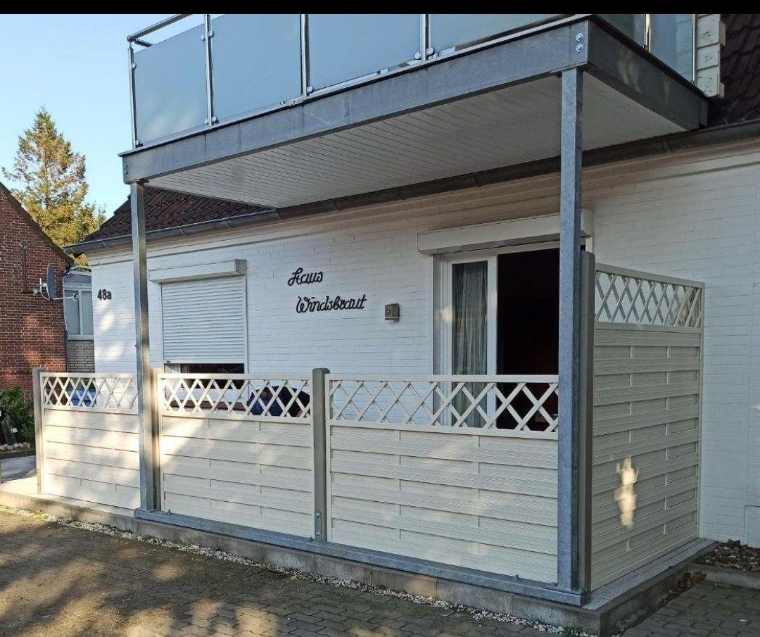 Wohnhaus mit Balkon und weißen Wänden. Sichtbar sind Fenster und Rollladen.