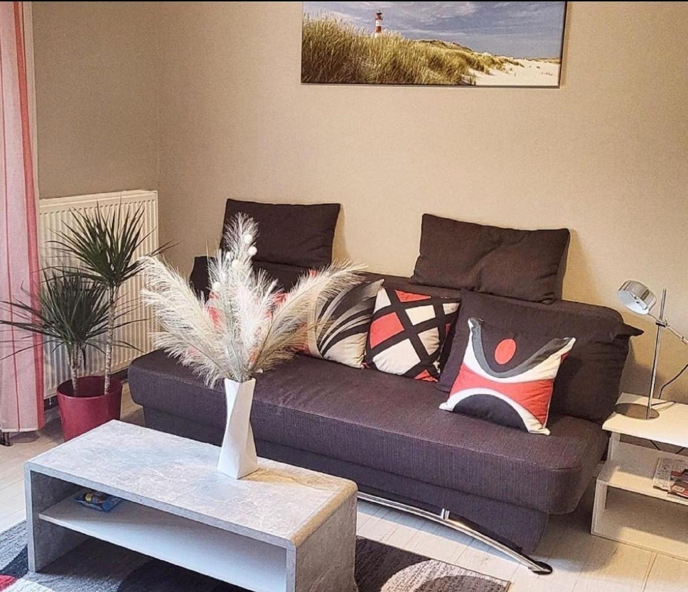 Ein Wohnzimmer mit grauem Sofa, dekorativen Kissen und einem Tisch mit Vasen.