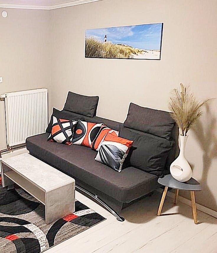 Ein Wohnzimmer mit grauem Sofa, modernem Beistelltisch und Wandbild.