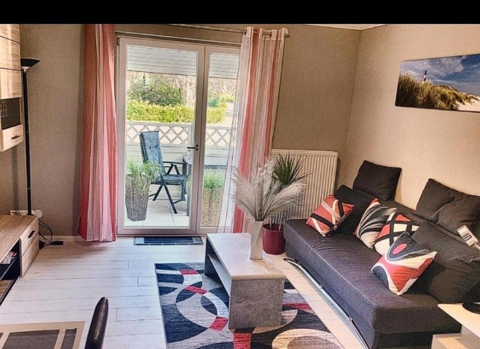 Wohnzimmer mit Sofa, Couchtisch und Balkon. Wandbild und Pflanzen.