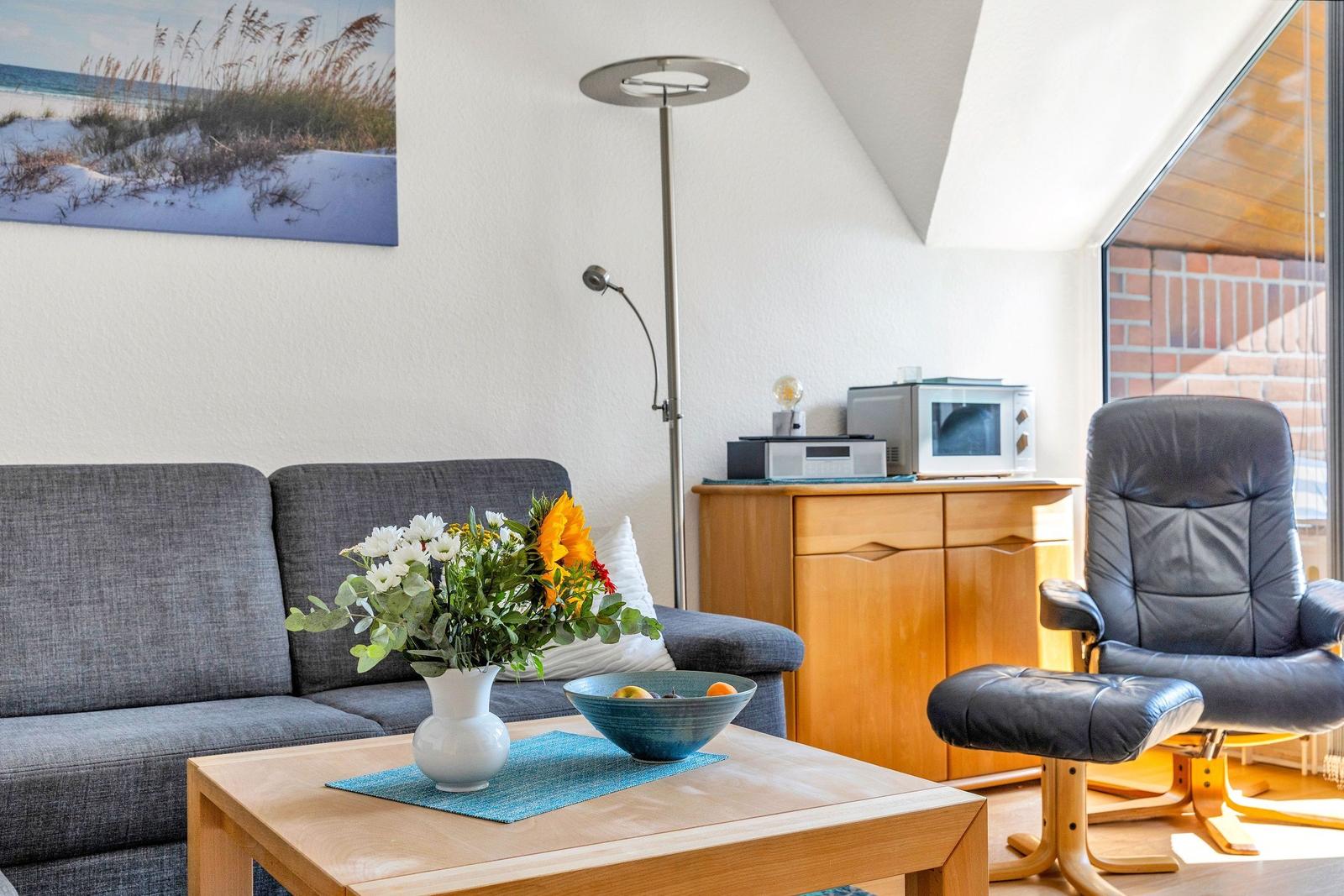 Wohnzimmer mit Sofa, Sessel, Couchtisch und Mikrowelle.