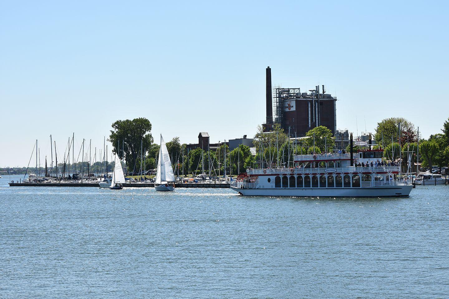 Schiffsanleger mit Segelbooten und Dampfschiff auf ruhigem Wasser.