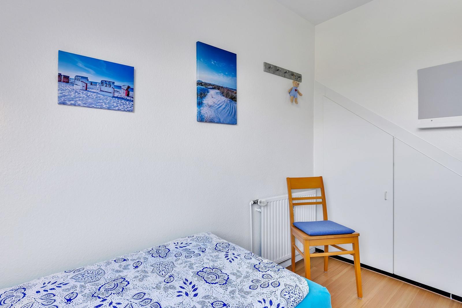 Schlafzimmer mit Bett, Stuhl und Wandbildern