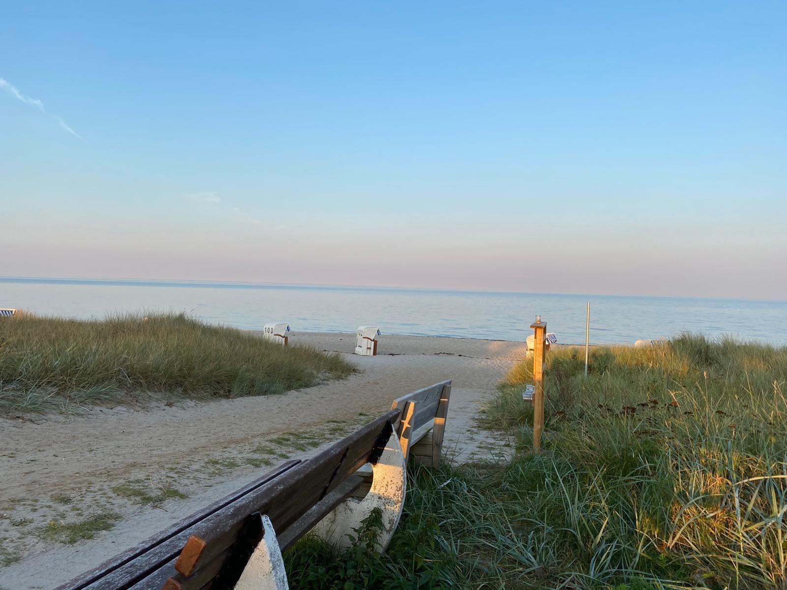 Weg zur Strandpromenade mit Dünen und Strandkörben. Blick auf ruhiges Meer.