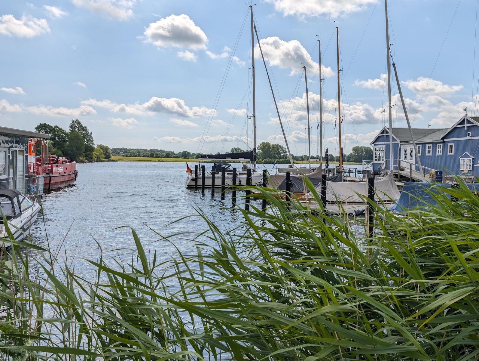Hafen mit Segelbooten und blauem Haus am Wasser.
