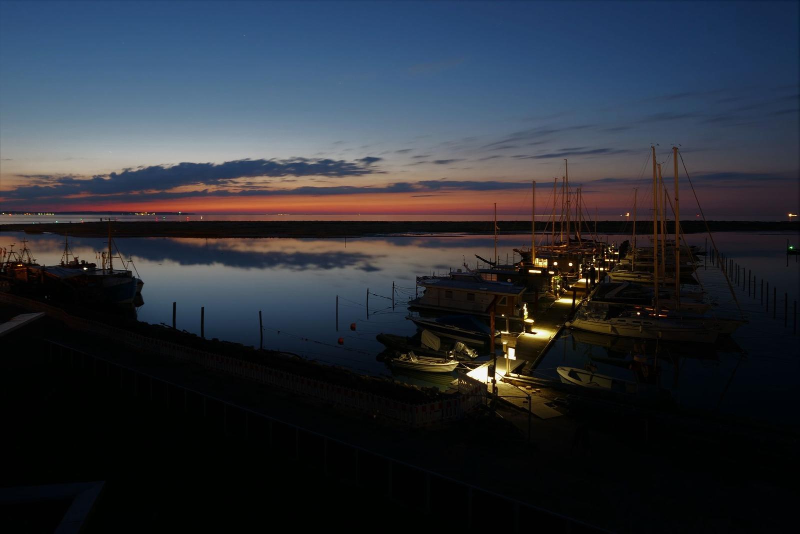 Abendlicher Hafen mit Booten und farbigem Himmel.