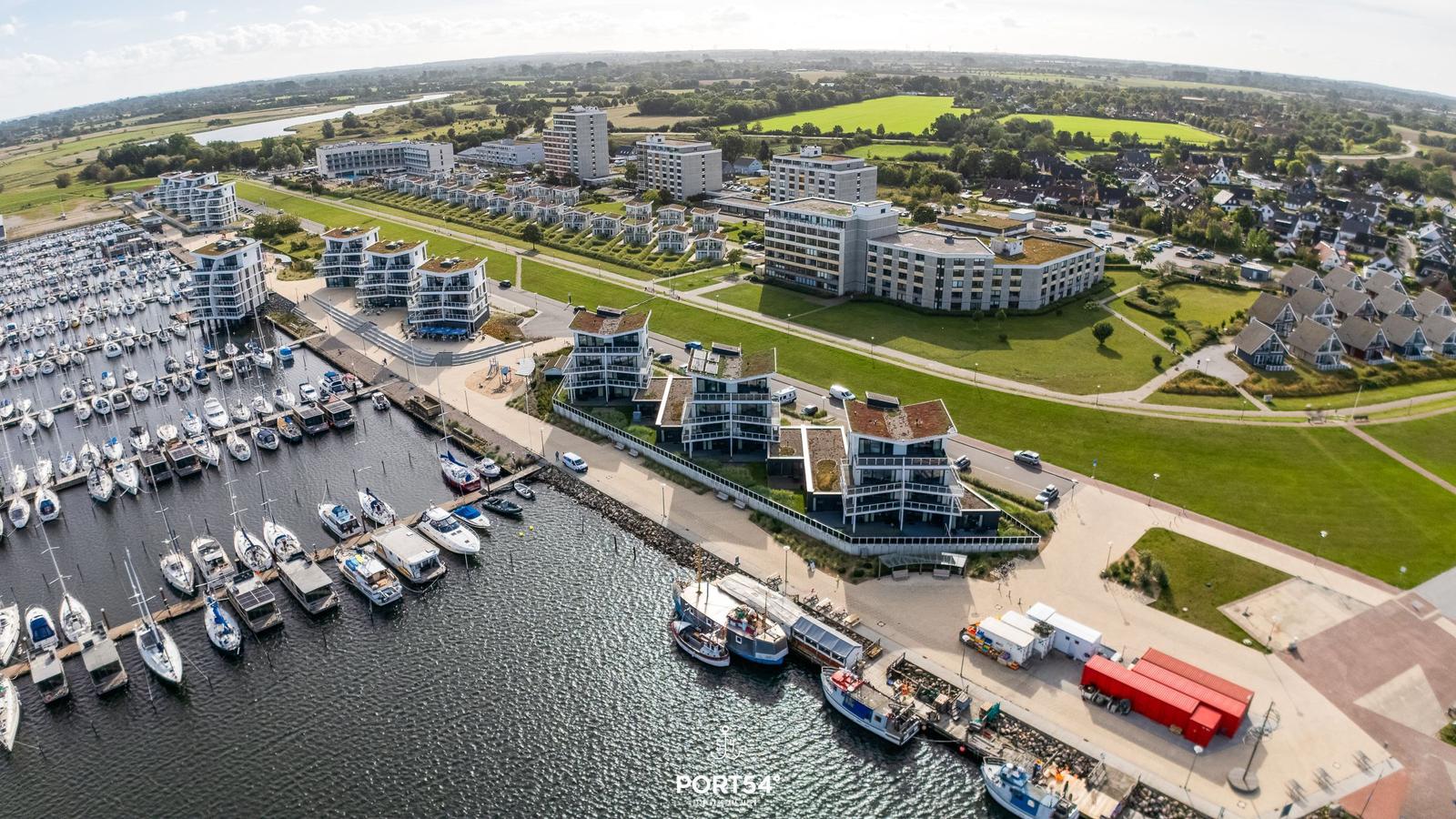 Aerial view of marina with boats and modern waterfront buildings.