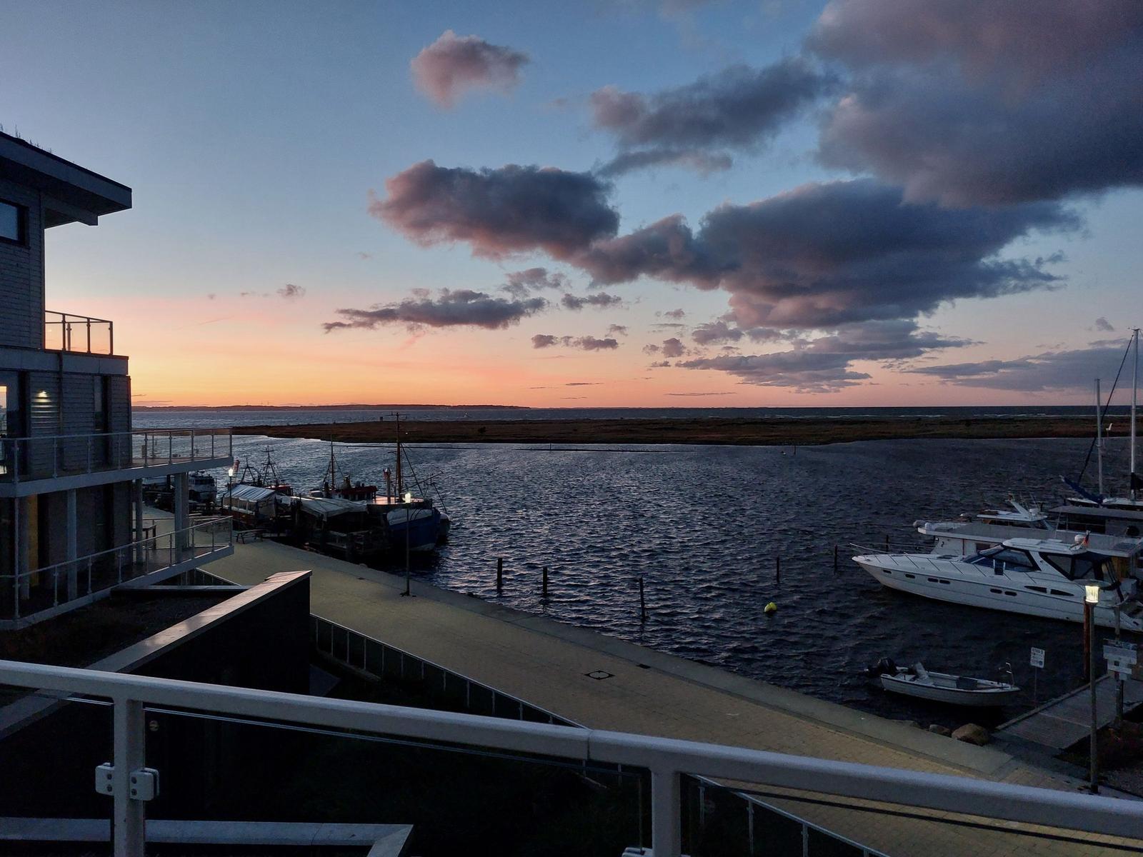 Sonnenuntergang über Hafen mit Booten und modernem Gebäude