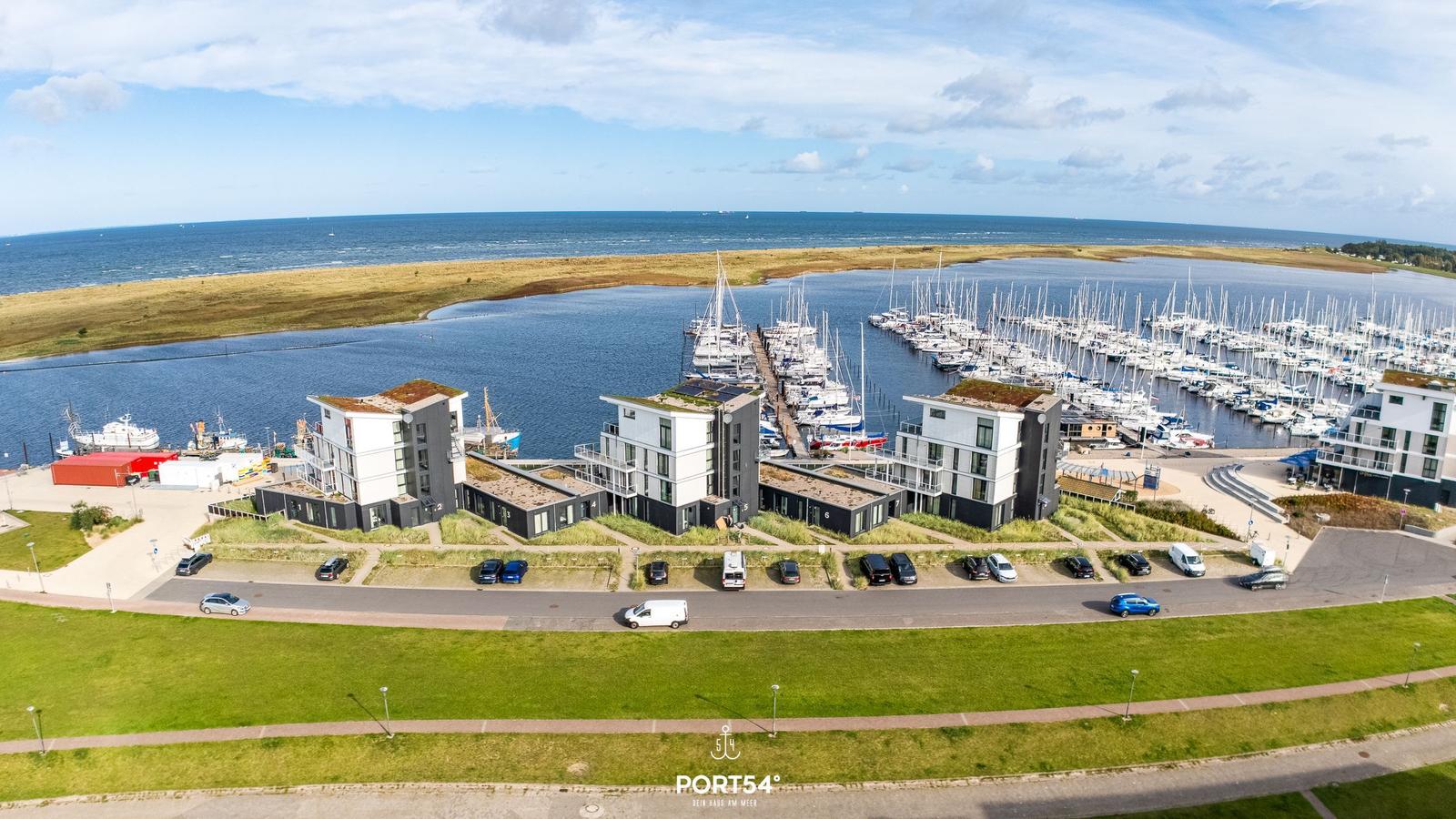 Modernes Haus am Hafen mit Booten und Grünflächen.