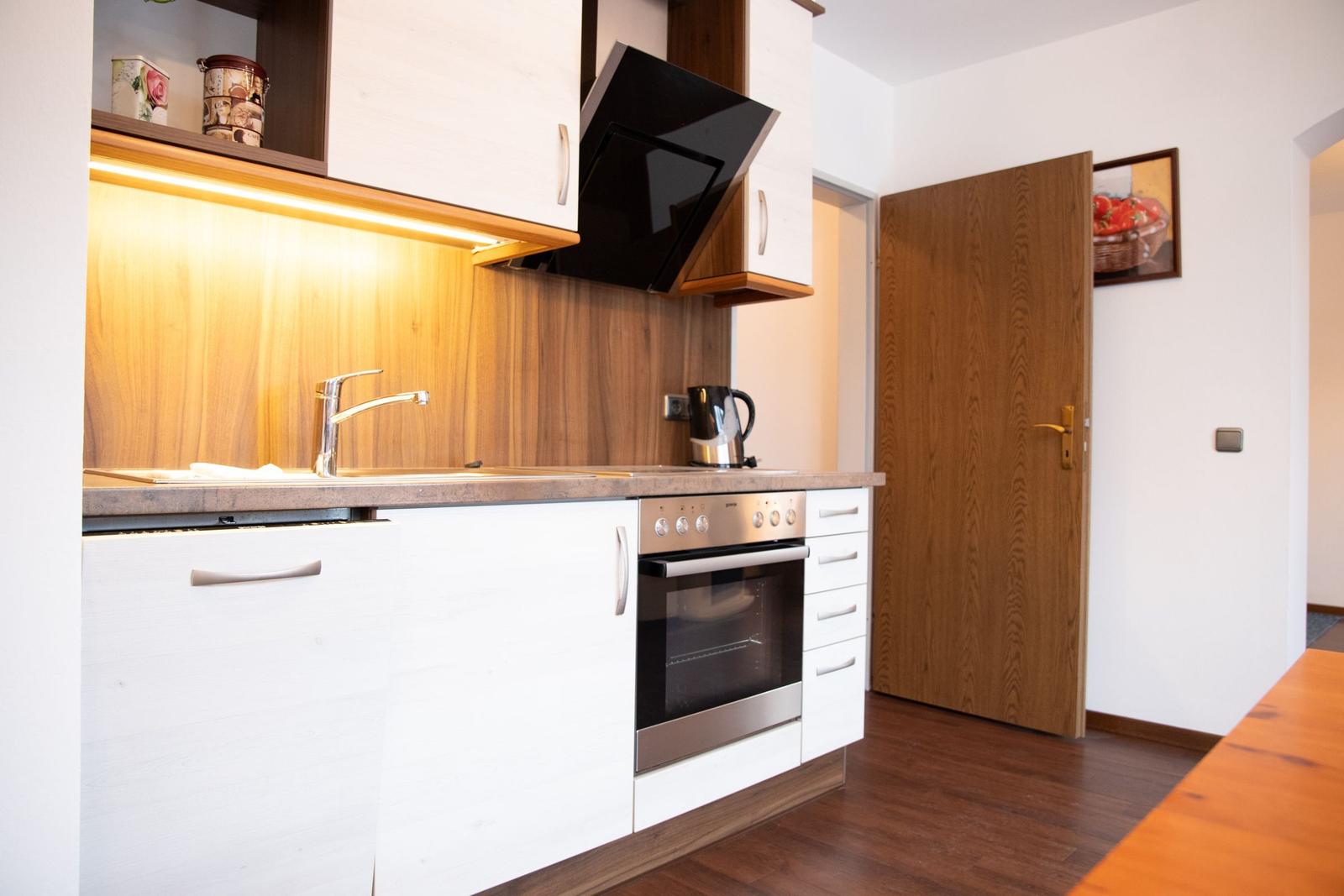 Küche mit Arbeitsplatte, Spüle, Herd und Dunstabzug.