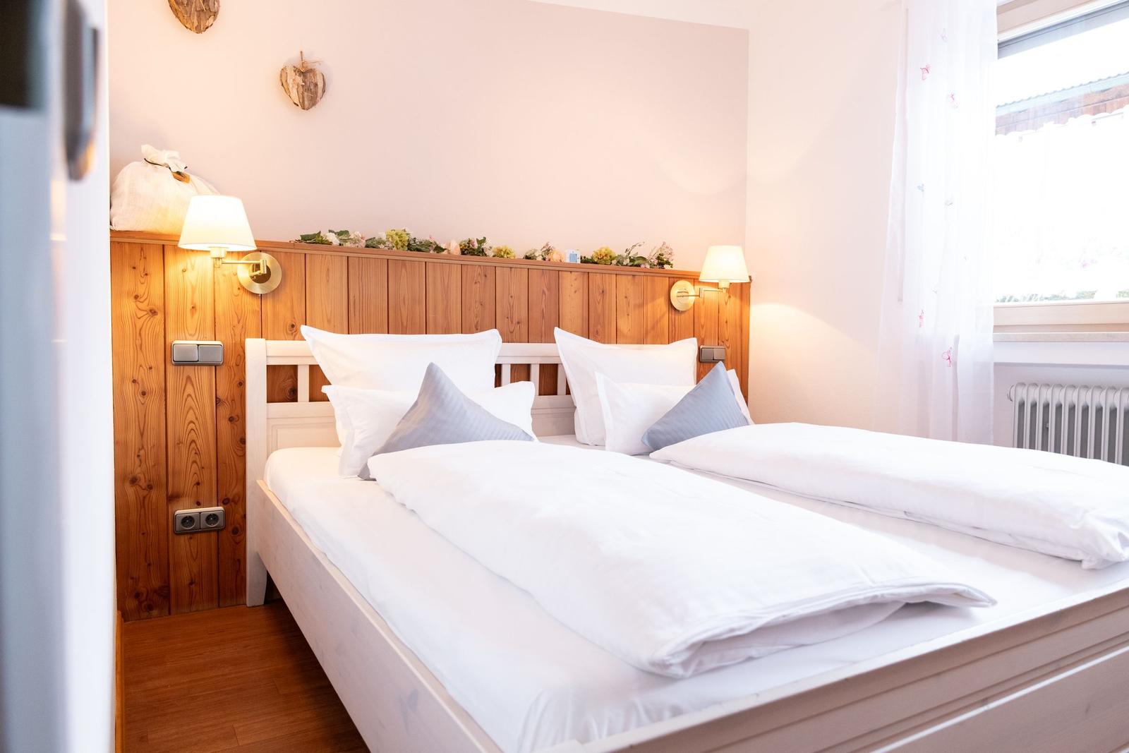 Schlafzimmer mit Doppelbett, Holzwand und Fenster