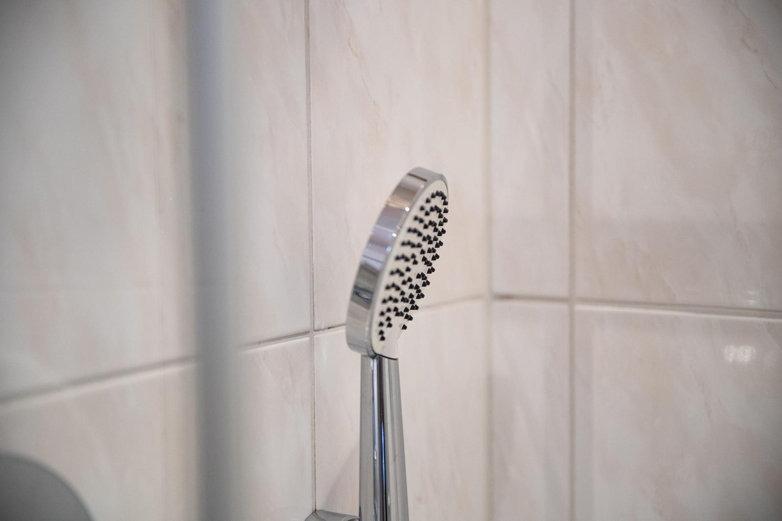 Handdusche mit Chromfinish an hellen Fliesenwand