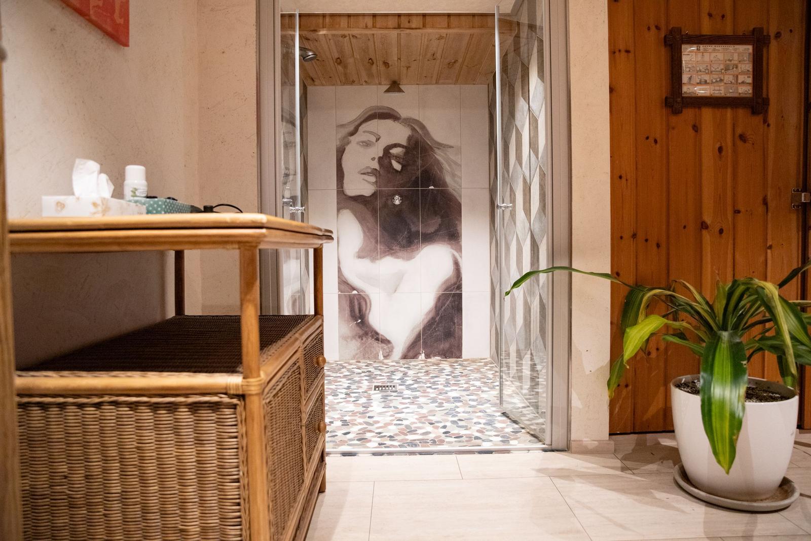 Dusche mit Bodenbelag aus Kieselsteinen und Wandbild einer Frau.