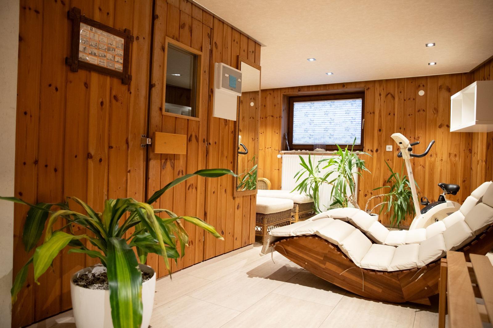 Raum mit Holzwand, Liege, Fahrradtrainer und Pflanzen