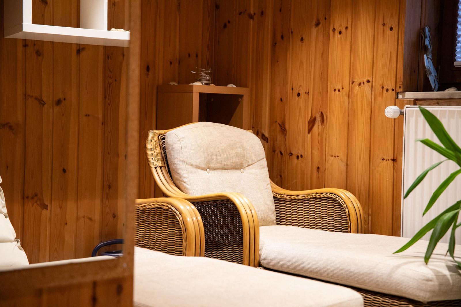 Rattan-Sessel mit Kissen in Holzvertäfelung