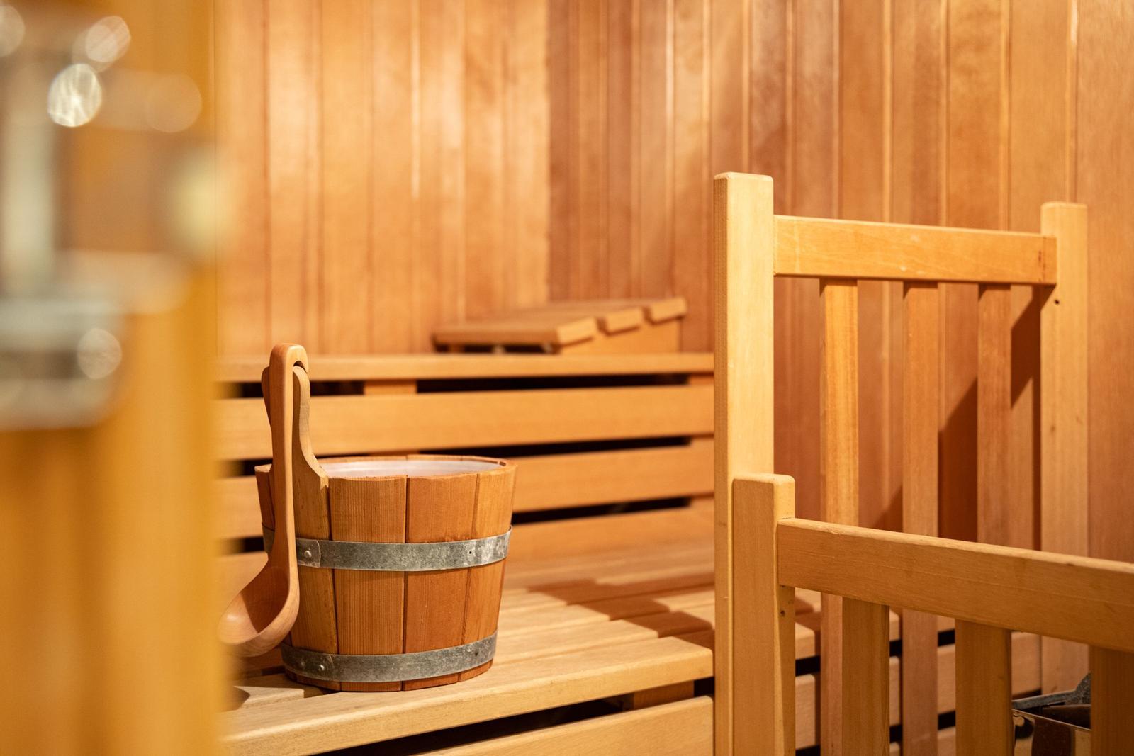 Sauna mit Holzbank und Eimer auf der Bank.