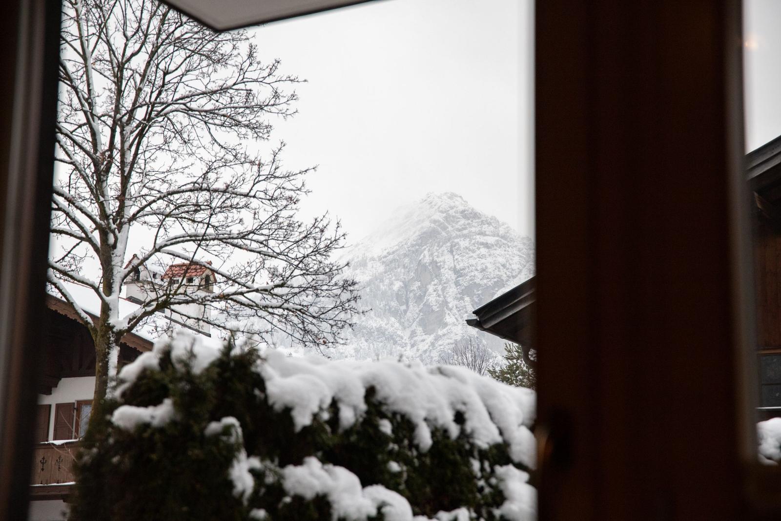 Schneebedeckte Bäume und Berge sind durch ein Fenster sichtbar.