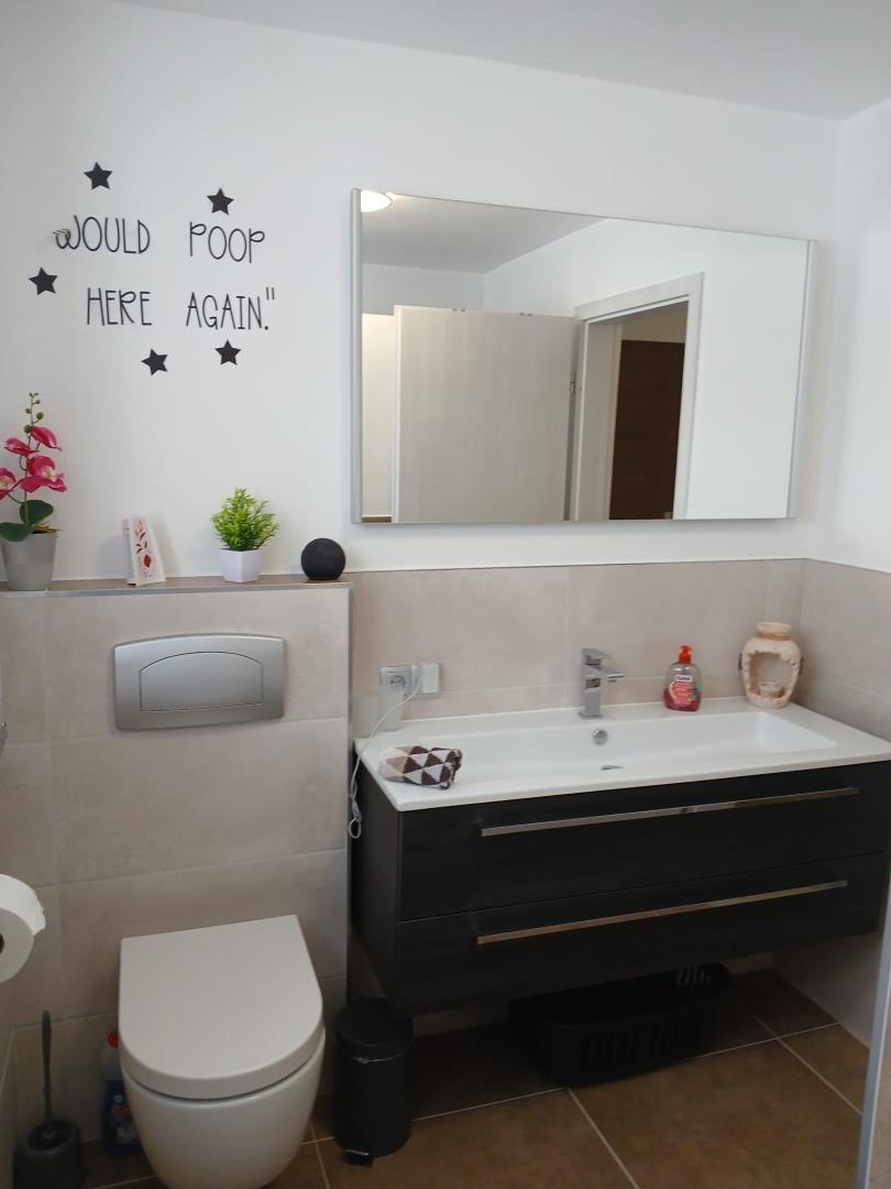 Bathroom with sink, mirror, and toilet. Wall decoration with stickers.
