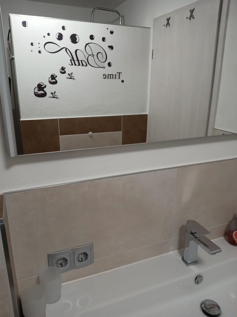 Bathroom with mirror, shower, and sink with faucet