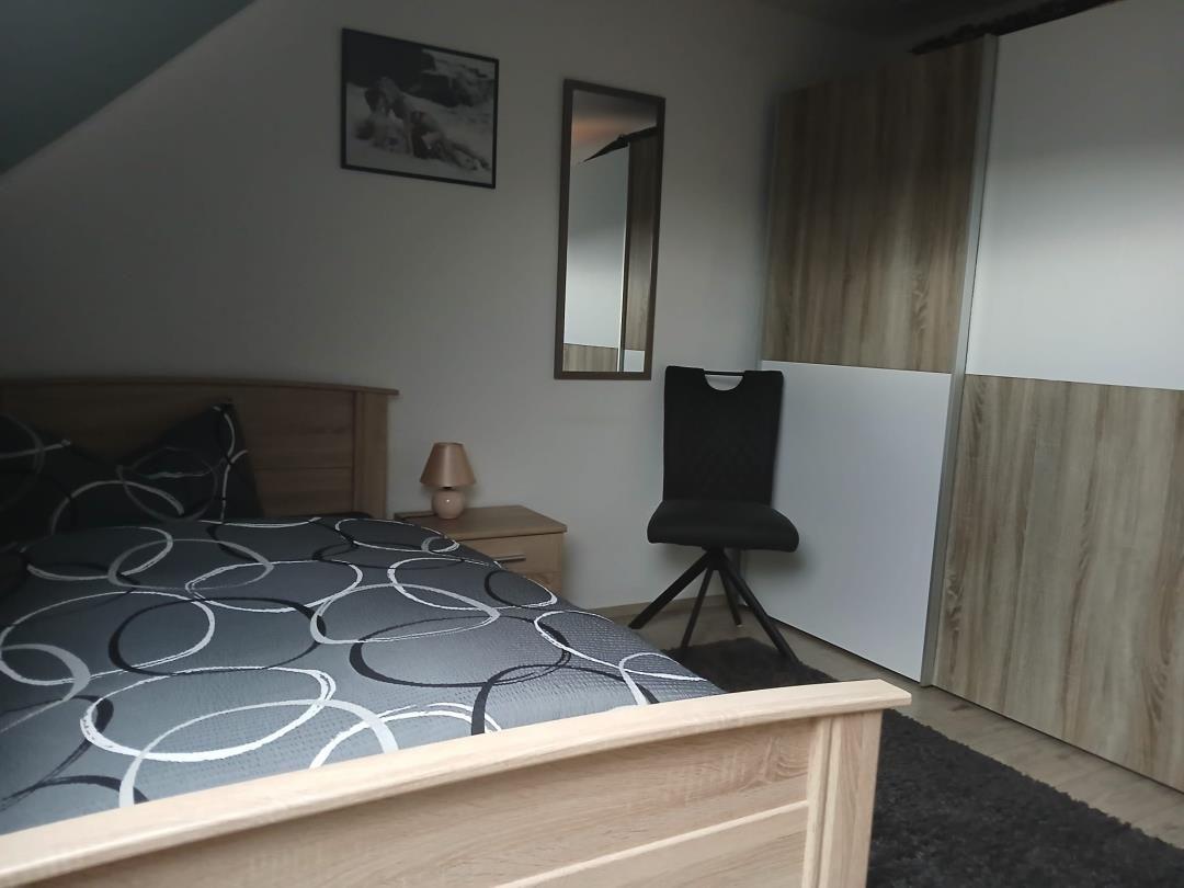 Bedroom with bed, office chair, and wardrobe