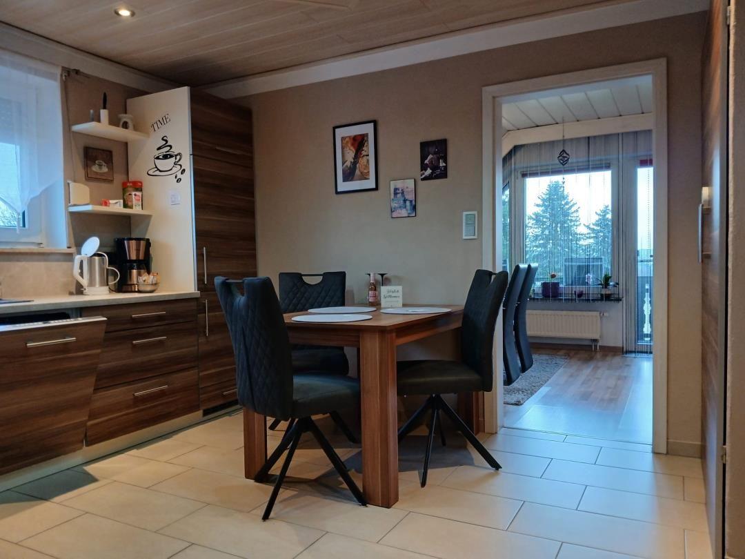 Dining area with table and chairs, kitchen, and view of balcony