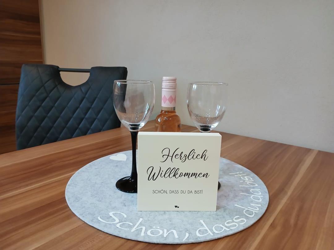 Table with welcome card, two wine glasses, and a bottle.