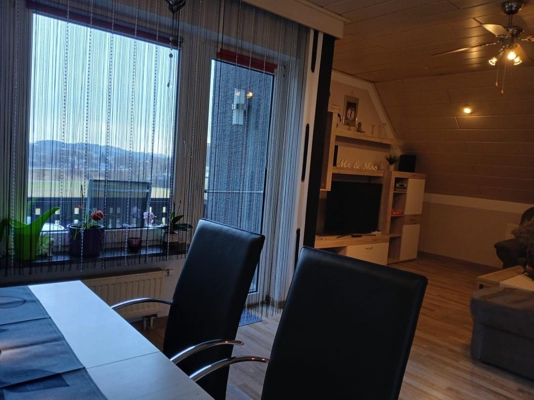 Dining area with view of landscape, living room with TV and wooden wall