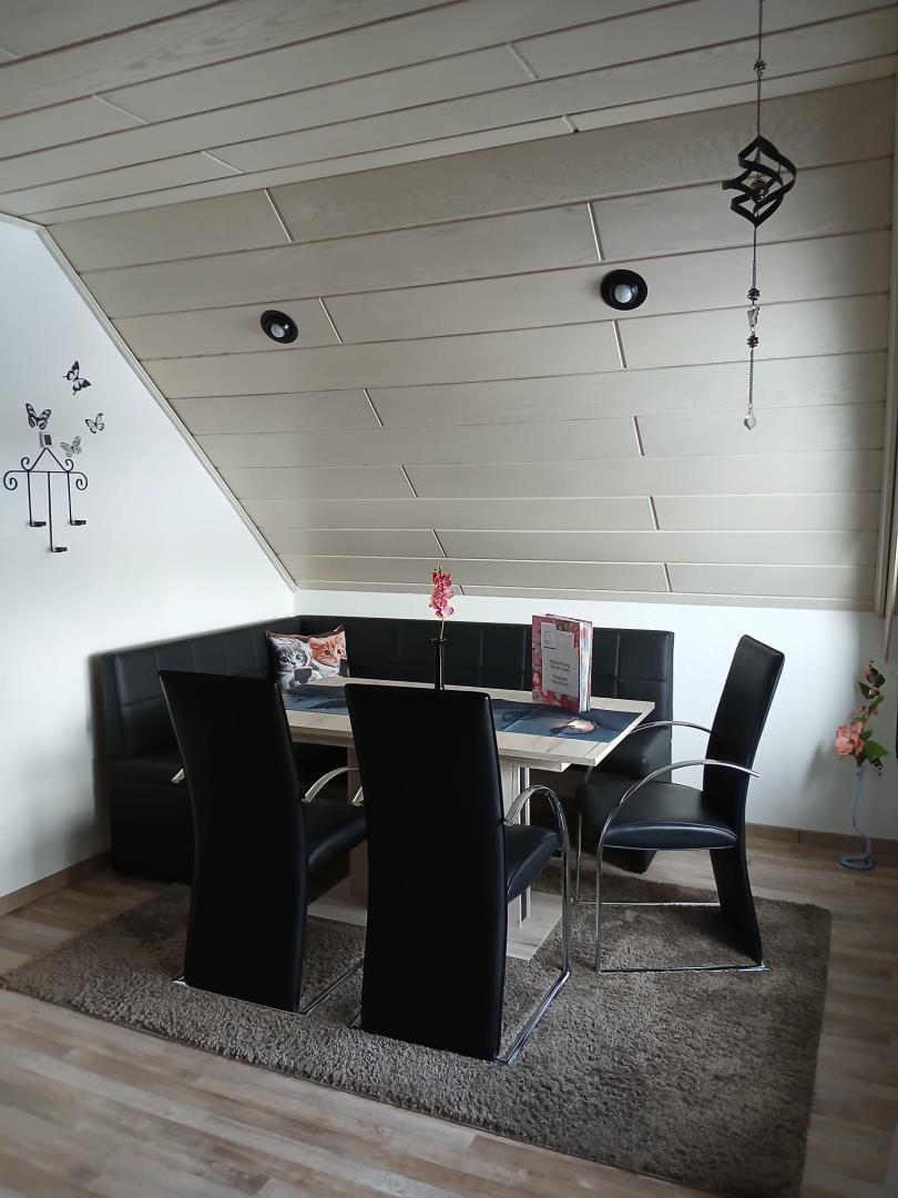 Dining room with bench, table and chairs under sloped ceiling
