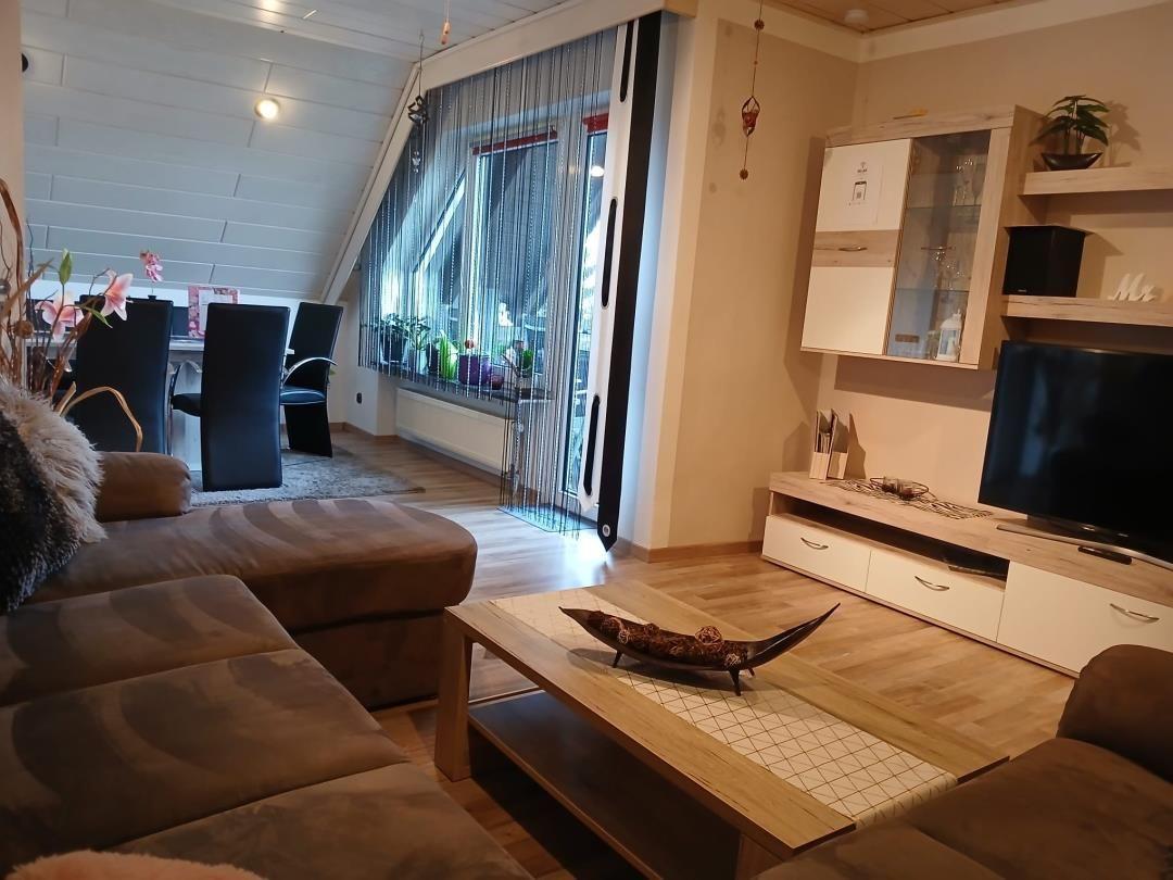 Living room with sofa, coffee table, and TV. Passage to kitchen with dining area.