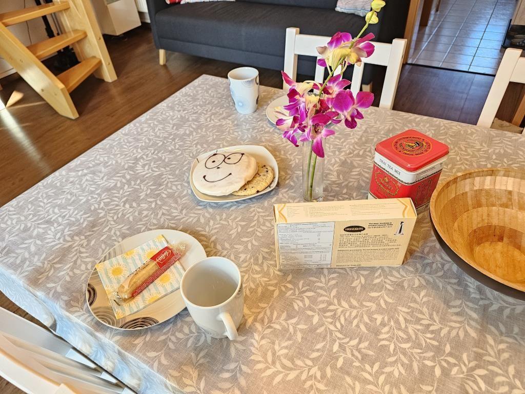 Table with tablecloth, mugs, flowers, and snacks