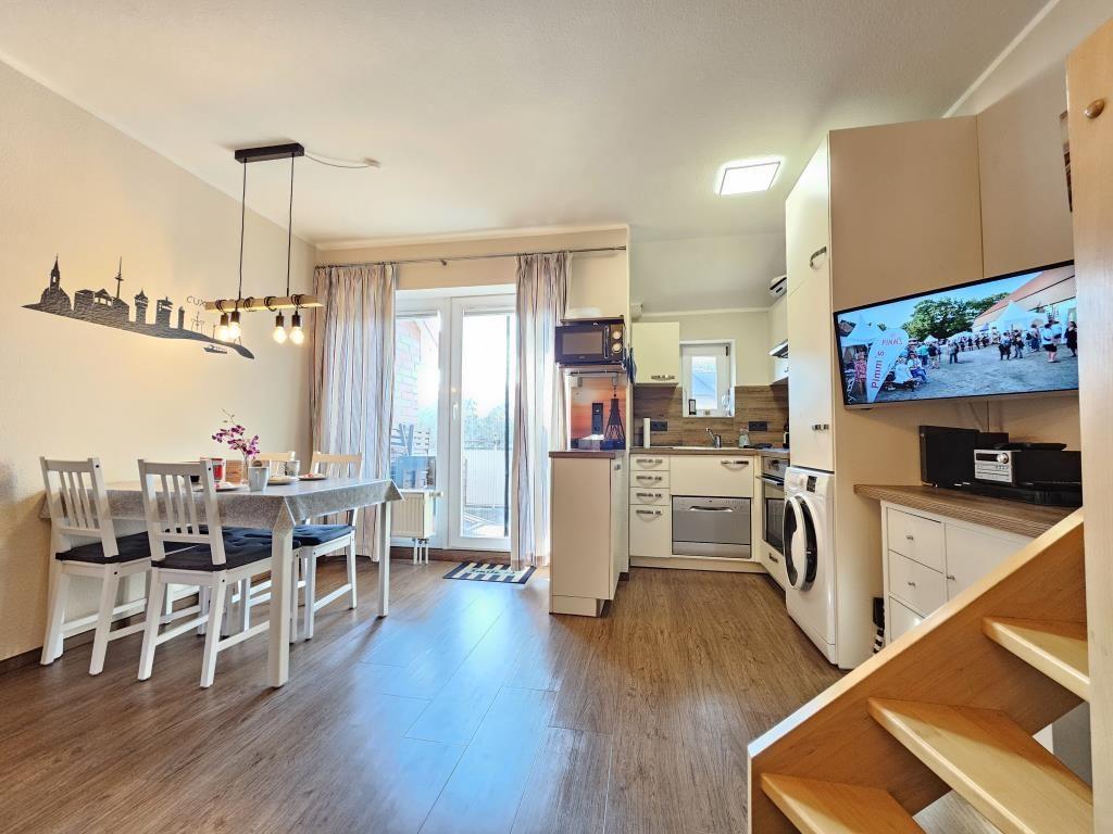 Living kitchen with dining table, TV, and balcony access.
