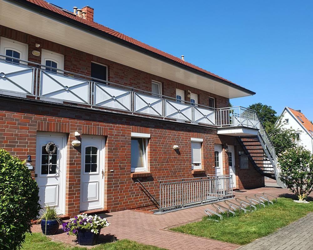 Two-story house with balcony, stairwell, and paved forecourt.