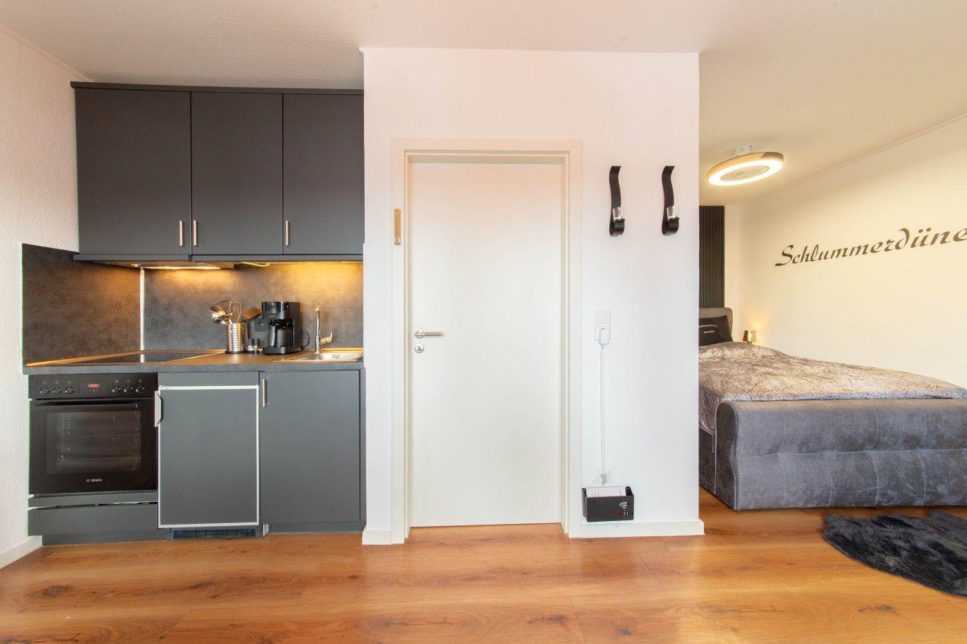 Küche mit Dunstabzug und Bett im Hintergrund