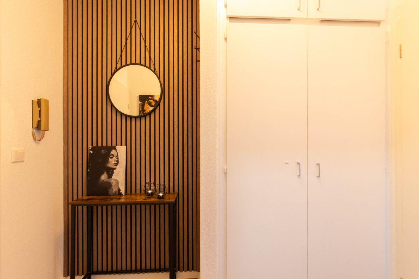 Eingangsbereich mit Holzwand, Spiegel und Kleiderschrank.