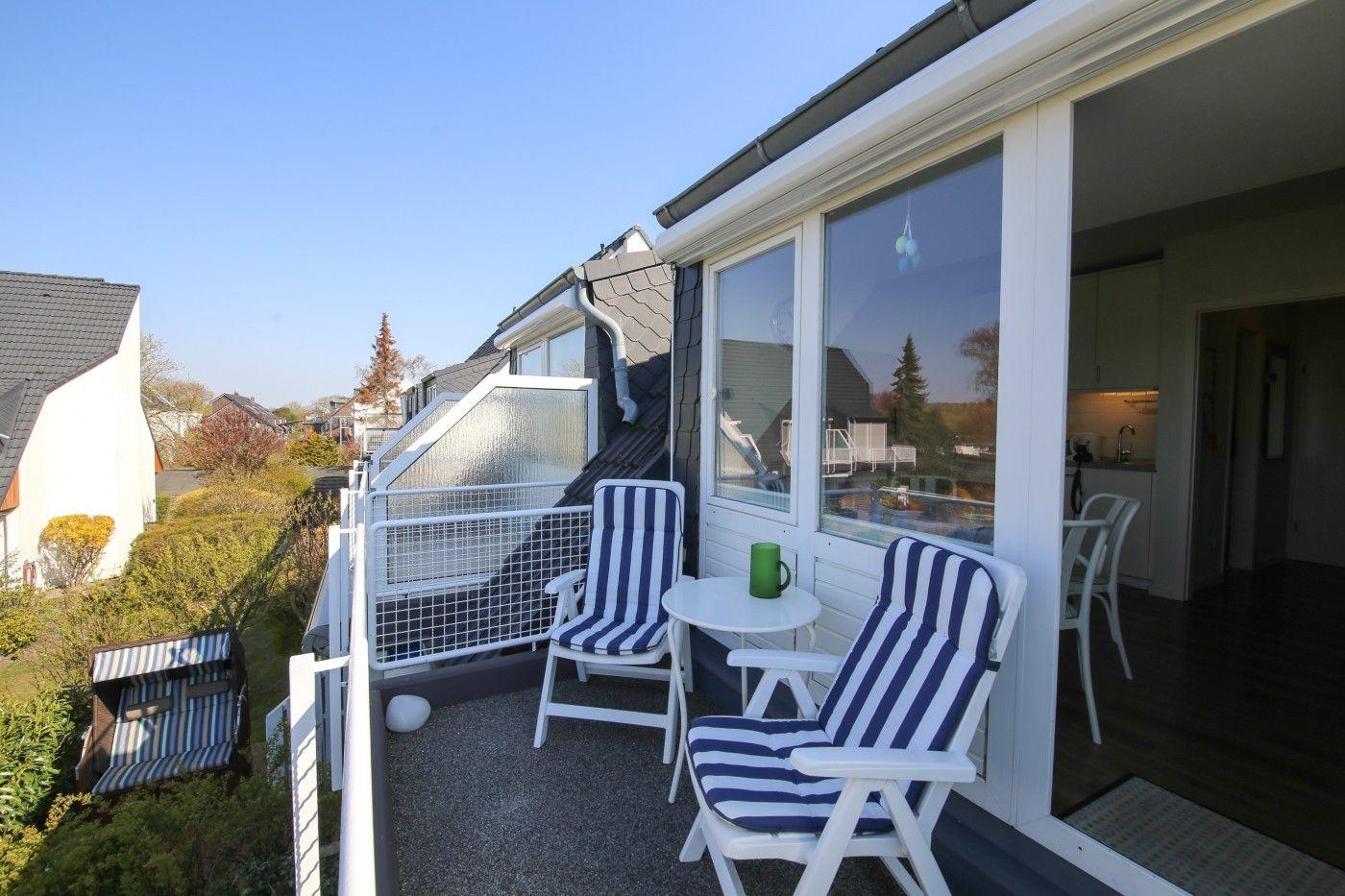 Terrasse mit zwei Stühlen und Tisch. Blick auf Garten und Nachbarhäuser.