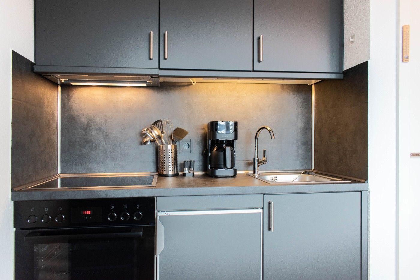 Küche mit Dunstabzug, Spüle, Kaffeemaschine und Backofen.