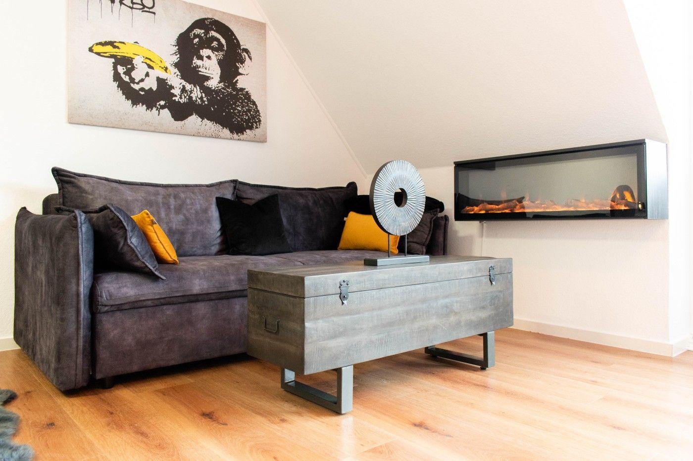 Ein Wohnzimmer mit grauem Sofa, Holzboden und moderner Wandheizung.
