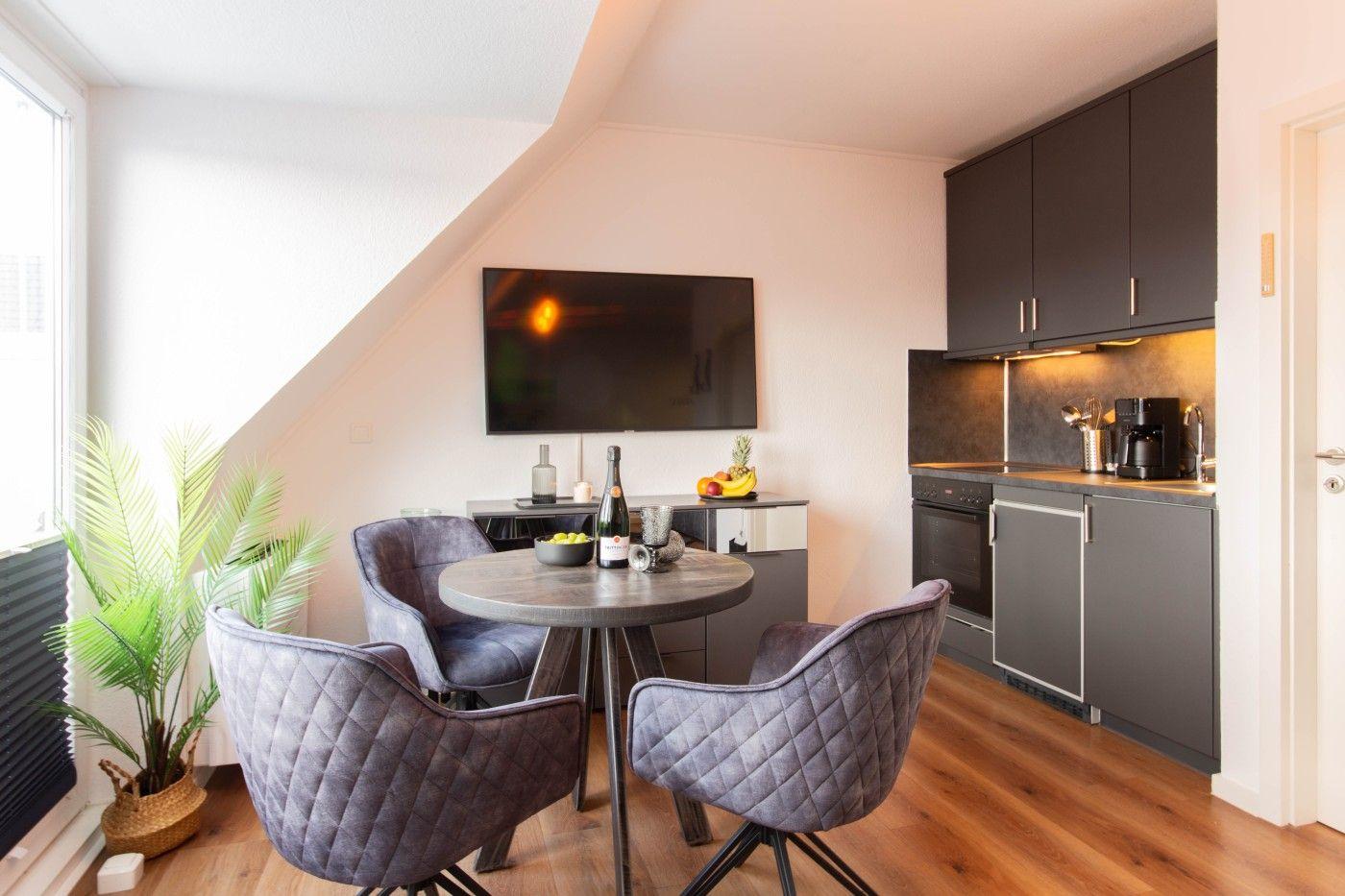 Küche mit Esstisch, Fernseher und Pflanze