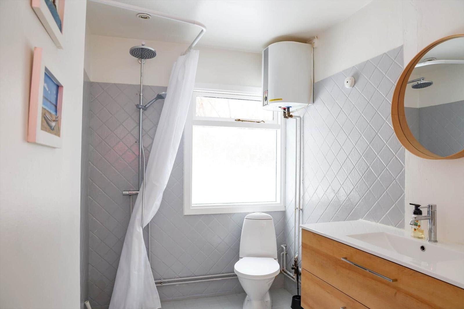 Badezimmer mit Dusche, Toilette und Waschbecken mit Spiegel.