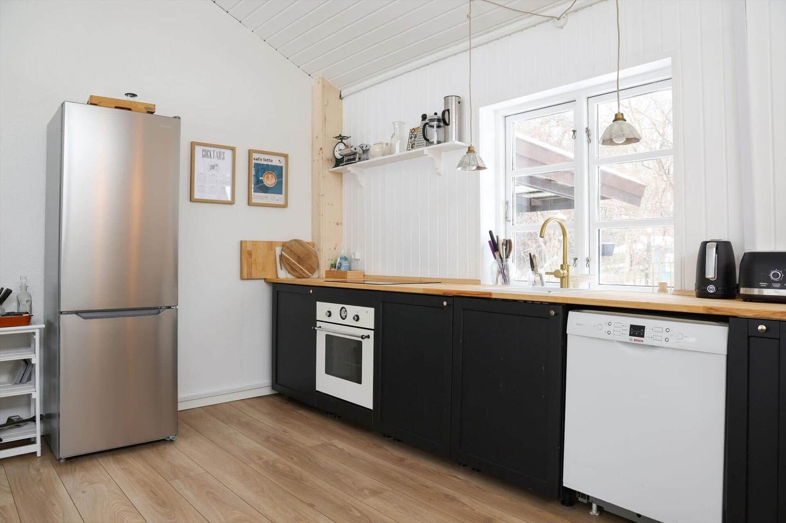 Küche mit Edelstahl-Kühlschrank, schwarzen Schränken und Holz Arbeitsplatte.
