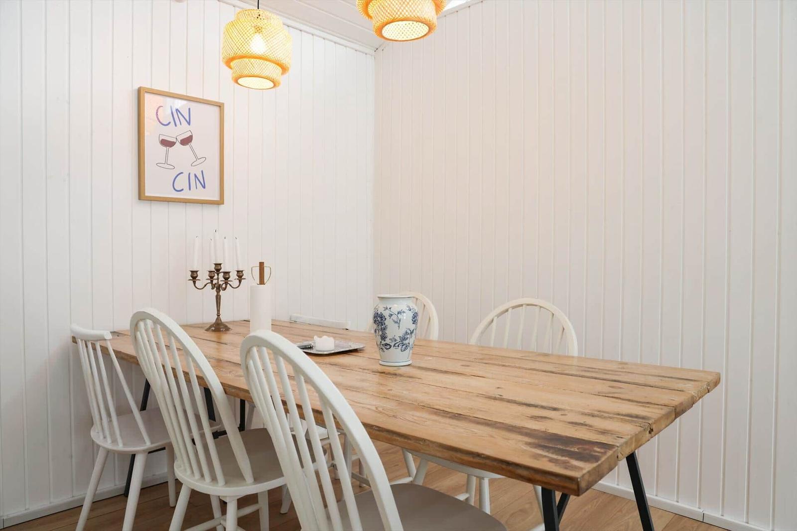 Esszimmer mit Holztisch, weißen Stühlen und Wandbild.
