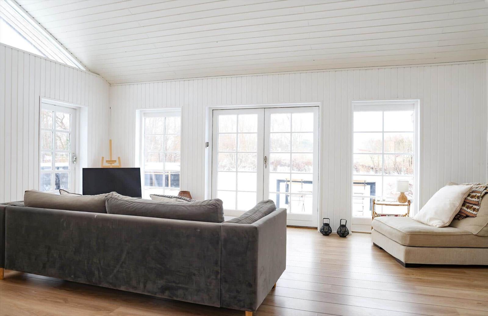 Wohnzimmer mit Sofa, Fenstern und Holzboden.