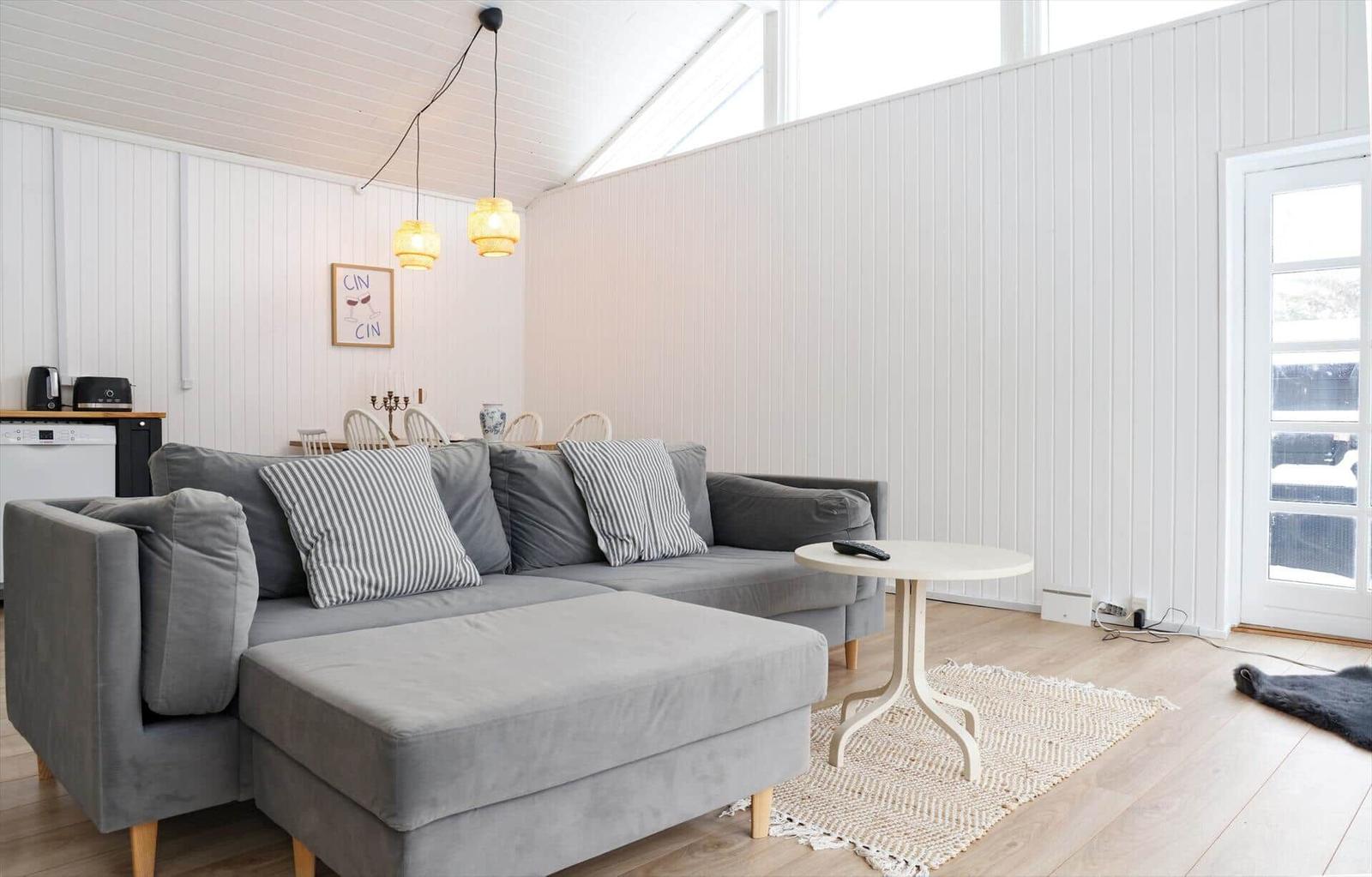 Ein Wohnzimmer mit grauem Sofa, weißer Couchtisch und Holzboden.