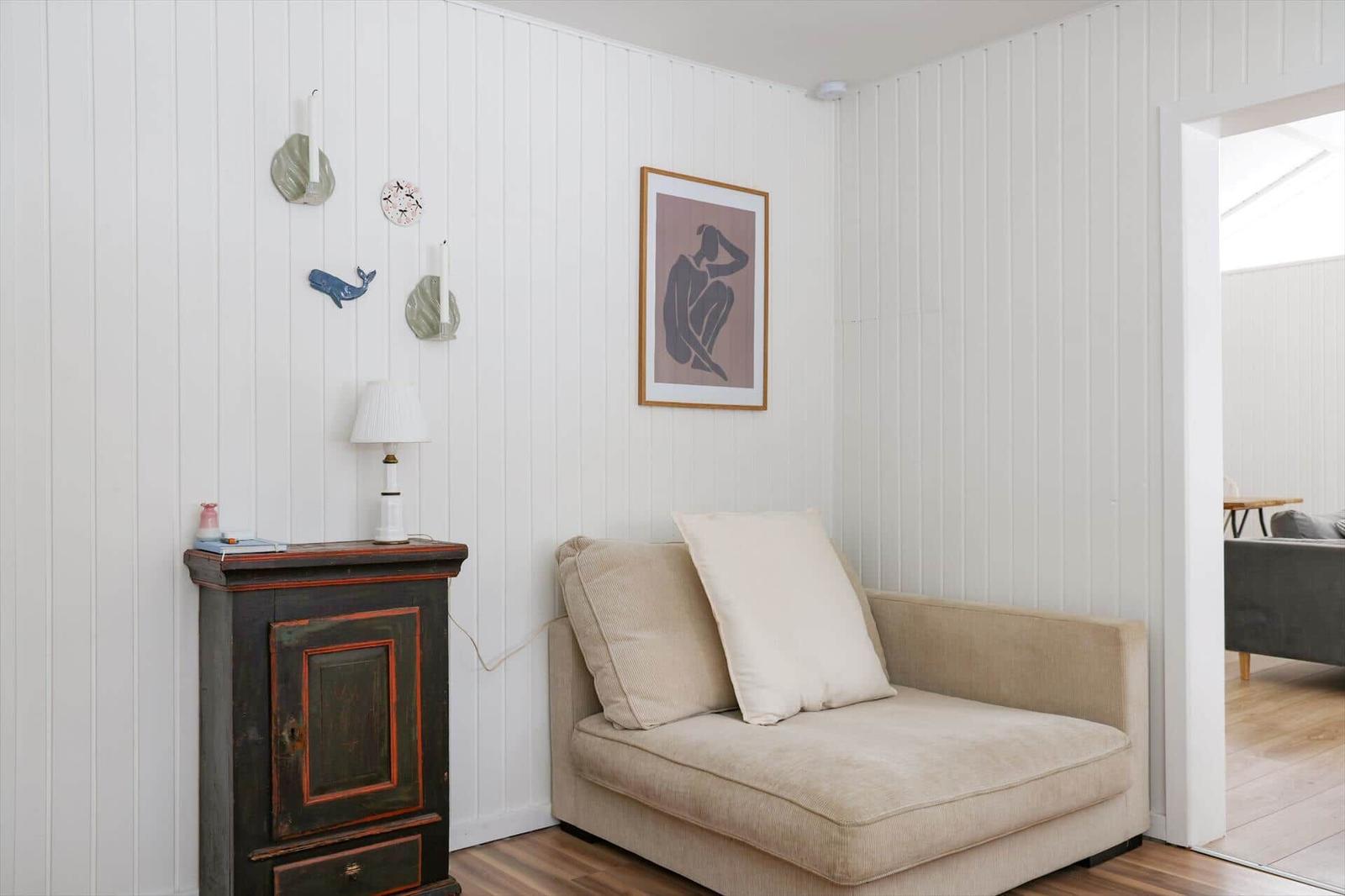 Ein Raum mit einem Sofa, einem dunklen Schrank und einer Wand mit Dekoration.