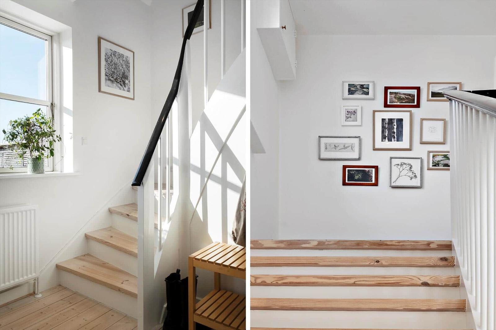 Staircase with wooden steps, wall pictures, and window with plant.