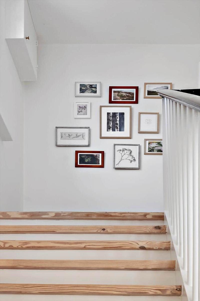 Light staircase with wooden steps and decorative wall arrangement.